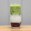 iced latte with blueberry compote, ceremonial-grade matcha, and oat milk in a tall glass, garnished with fresh blueberries and mint.