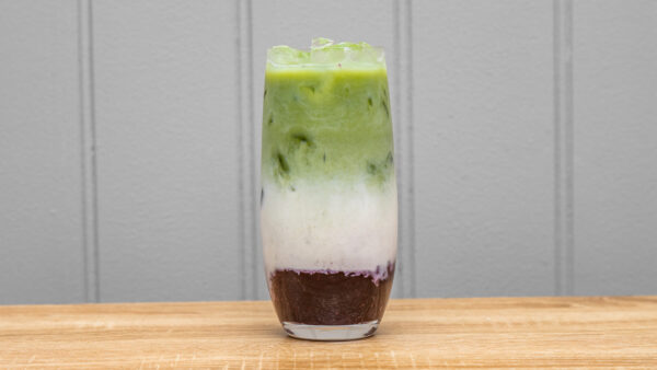 iced latte with blueberry compote, ceremonial-grade matcha, and oat milk in a tall glass, garnished with fresh blueberries and mint.
